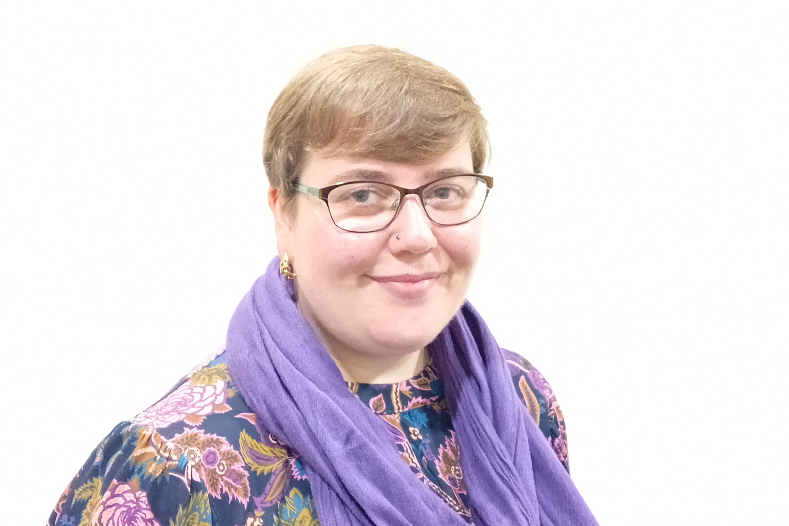 Photograph of employability client, Rebecca, smiling at the camera. She has short pixie cut hair, glasses, is wearing a purple scarf and a multicolour floral patterned top. Photograph of employability client, Rebecca, smiling at the camera. She has short pixie cut hair, glasses, is wearing a purple scarf and a multicolour floral patterned top.