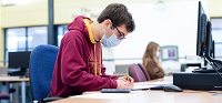 Male student sitting at computer desk studying