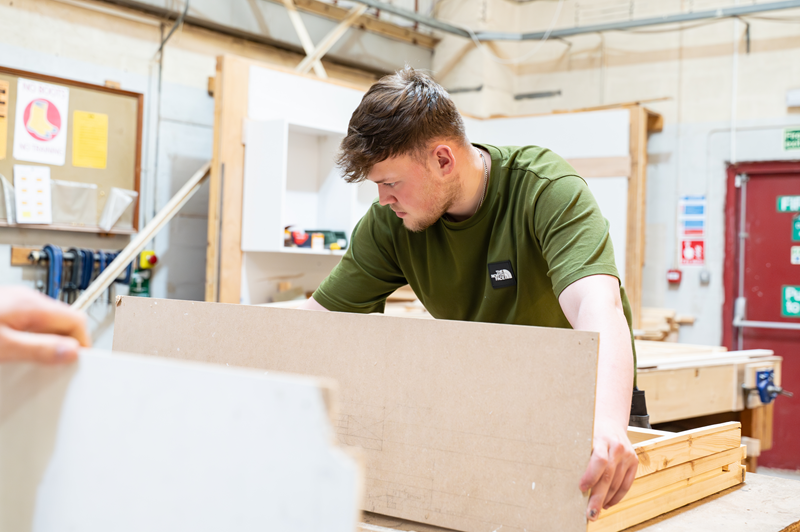 Photo of a male working on a piece of joinery equipment in a wiorkshop