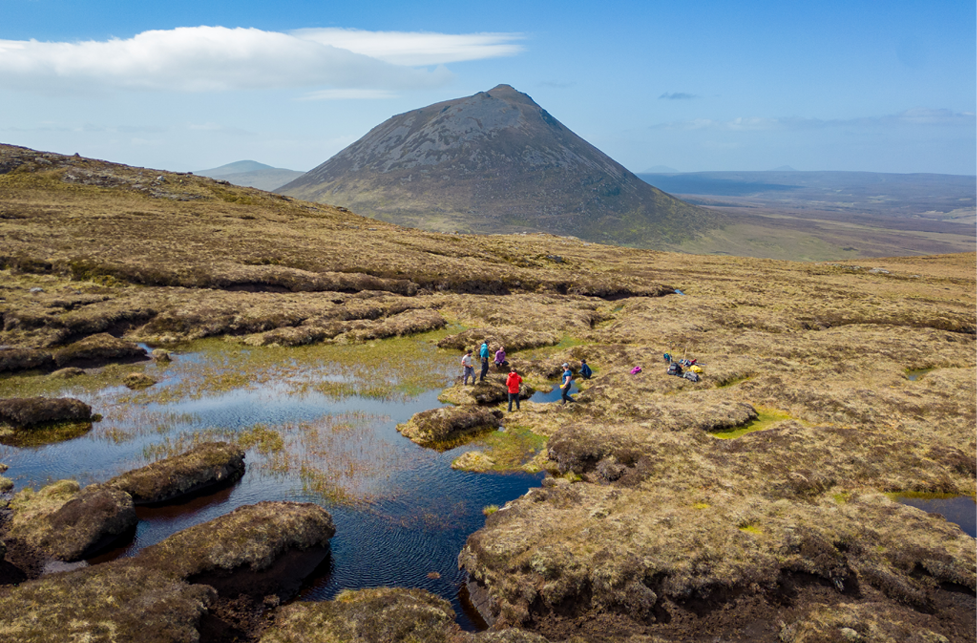 People waking beside a loch beside a mountain in rural Scotland